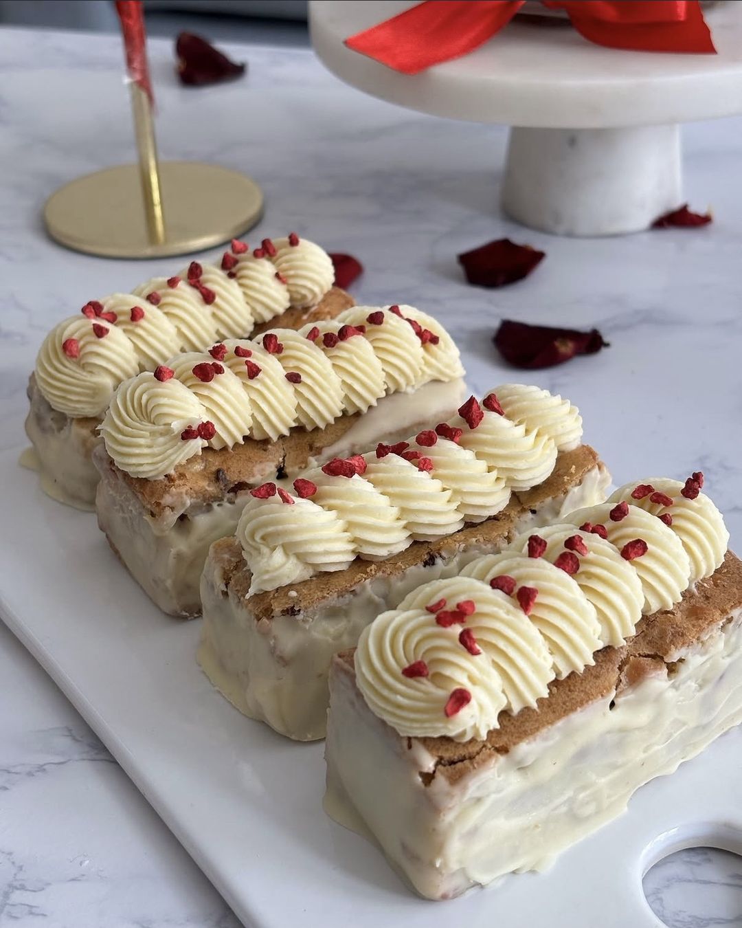 White chocolate blondie bars topped with piped cream and freeze-dried raspberry