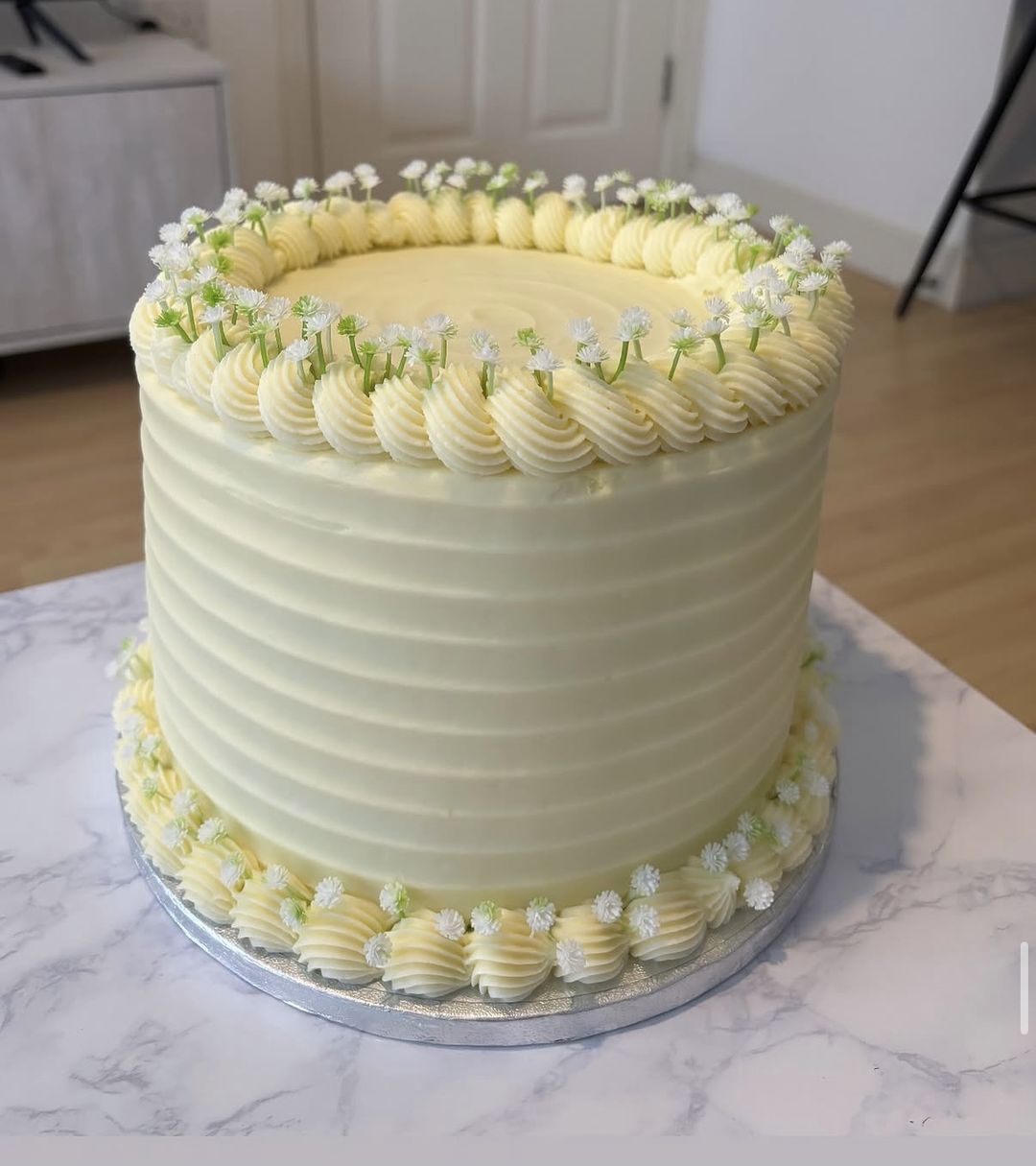 Tall ivory cake with combed sides, shell borders and tiny white flowers (photo 1 of 2)