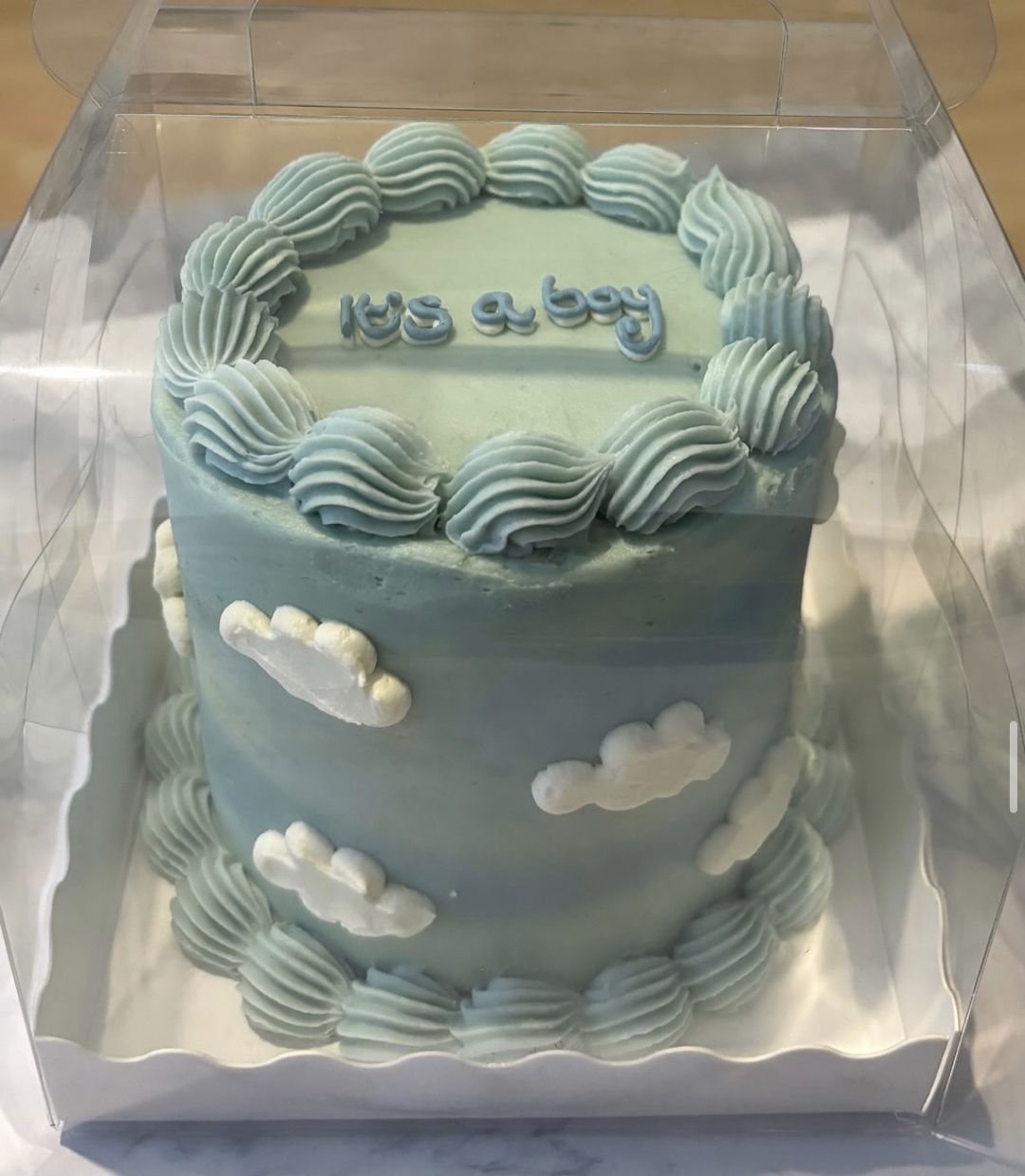 Pale blue bento cake with piped clouds and “It’s a boy” on top
