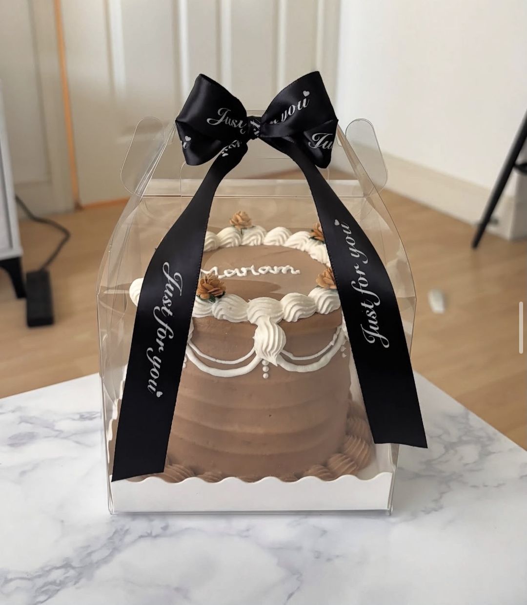 Chocolate-brown vintage bento with white piped garlands and “Mariam” on top, tied with a black ribbon (photo 1 of 2)