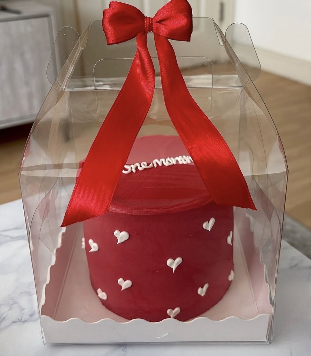 Red bento cake with white piped hearts and “One month” on top, tied with a red satin bow (photo 1 of 2)
