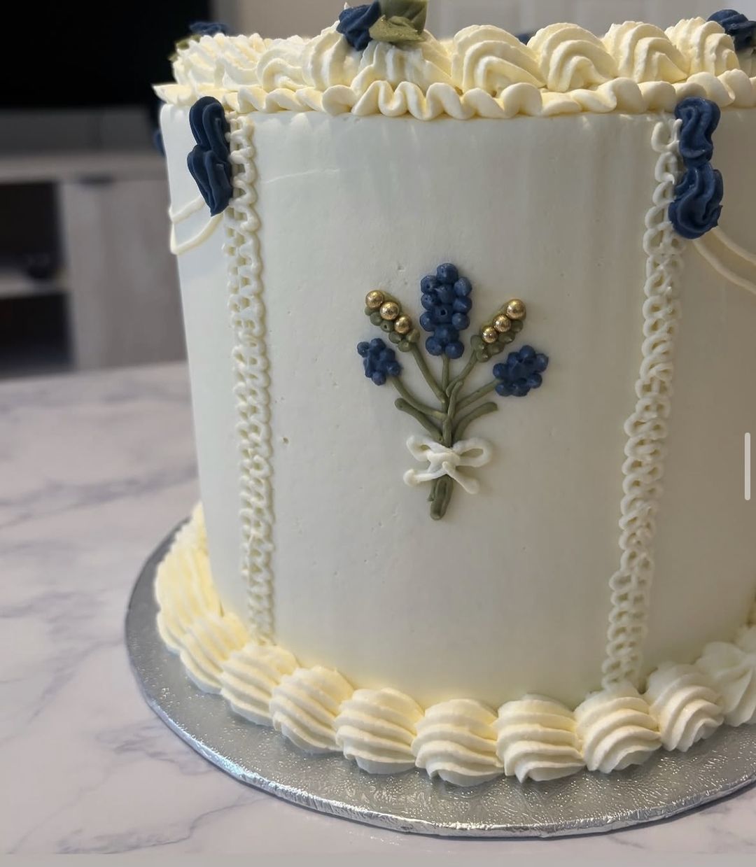 Tall white cake with blue piped flower bouquets, ivory borders and “Until the ink dries” on top (photo 1 of 2)