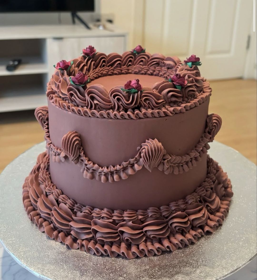 Chocolate vintage cake with ruffled piping, swags and small red roses on top (photo 1 of 3)