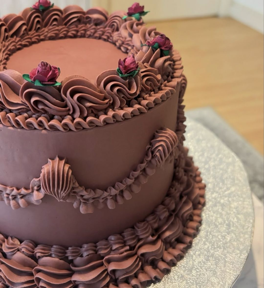 Chocolate vintage cake with ruffled piping, swags and small red roses on top (photo 2 of 3)