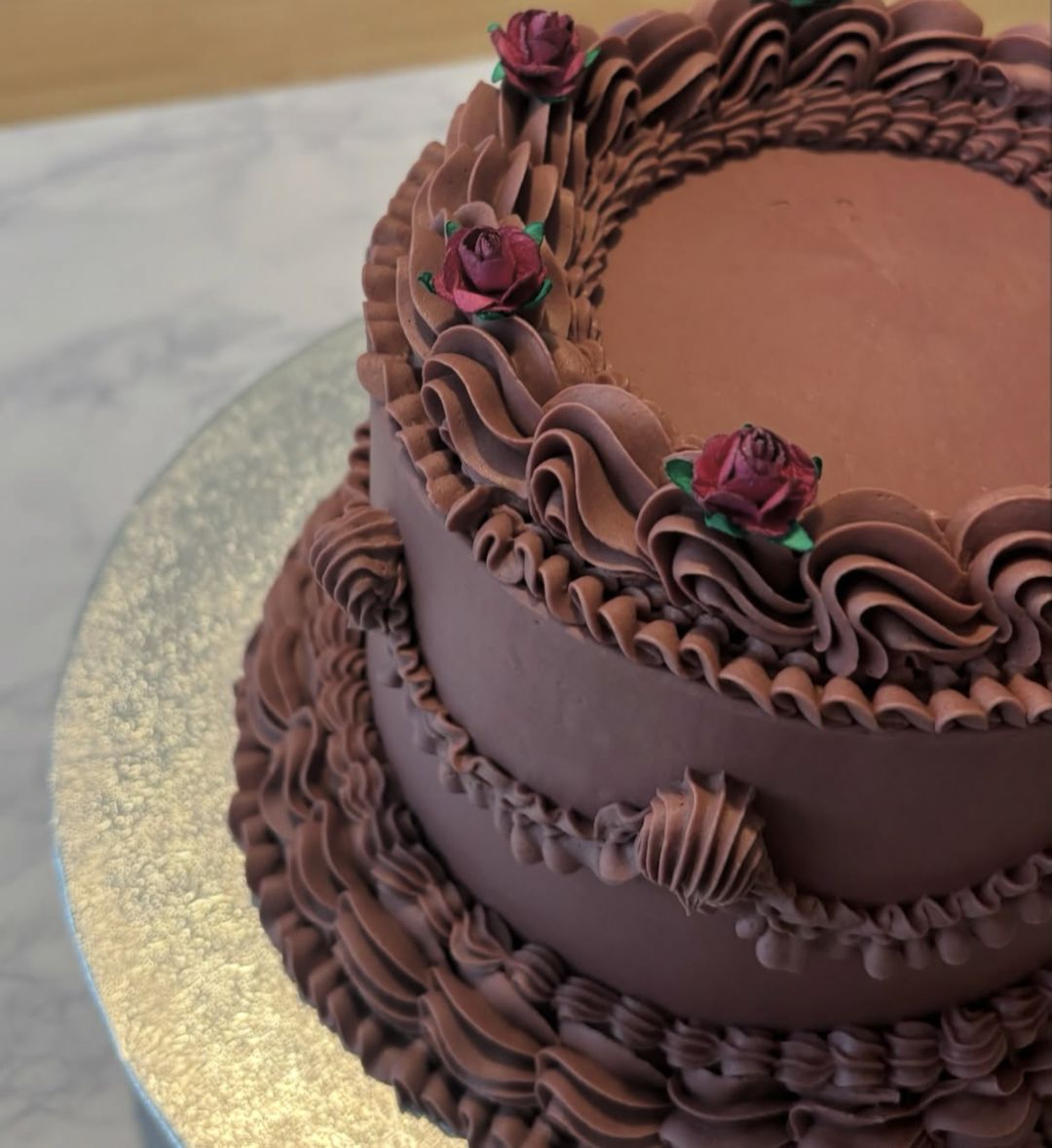 Chocolate vintage cake with ruffled piping, swags and small red roses on top (photo 3 of 3)