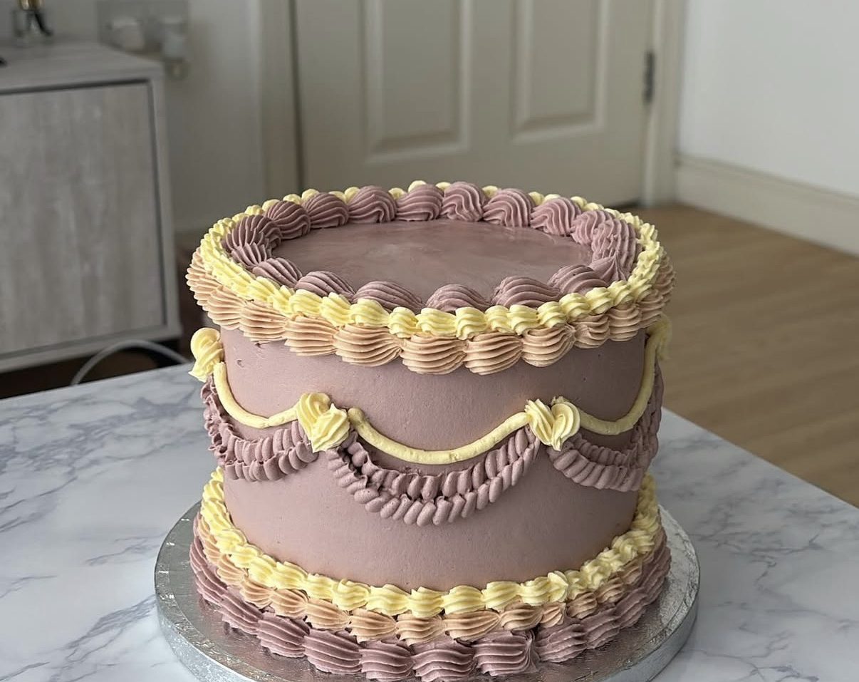 Mauve vintage cake with butter-yellow and lilac shell piping and swag garlands